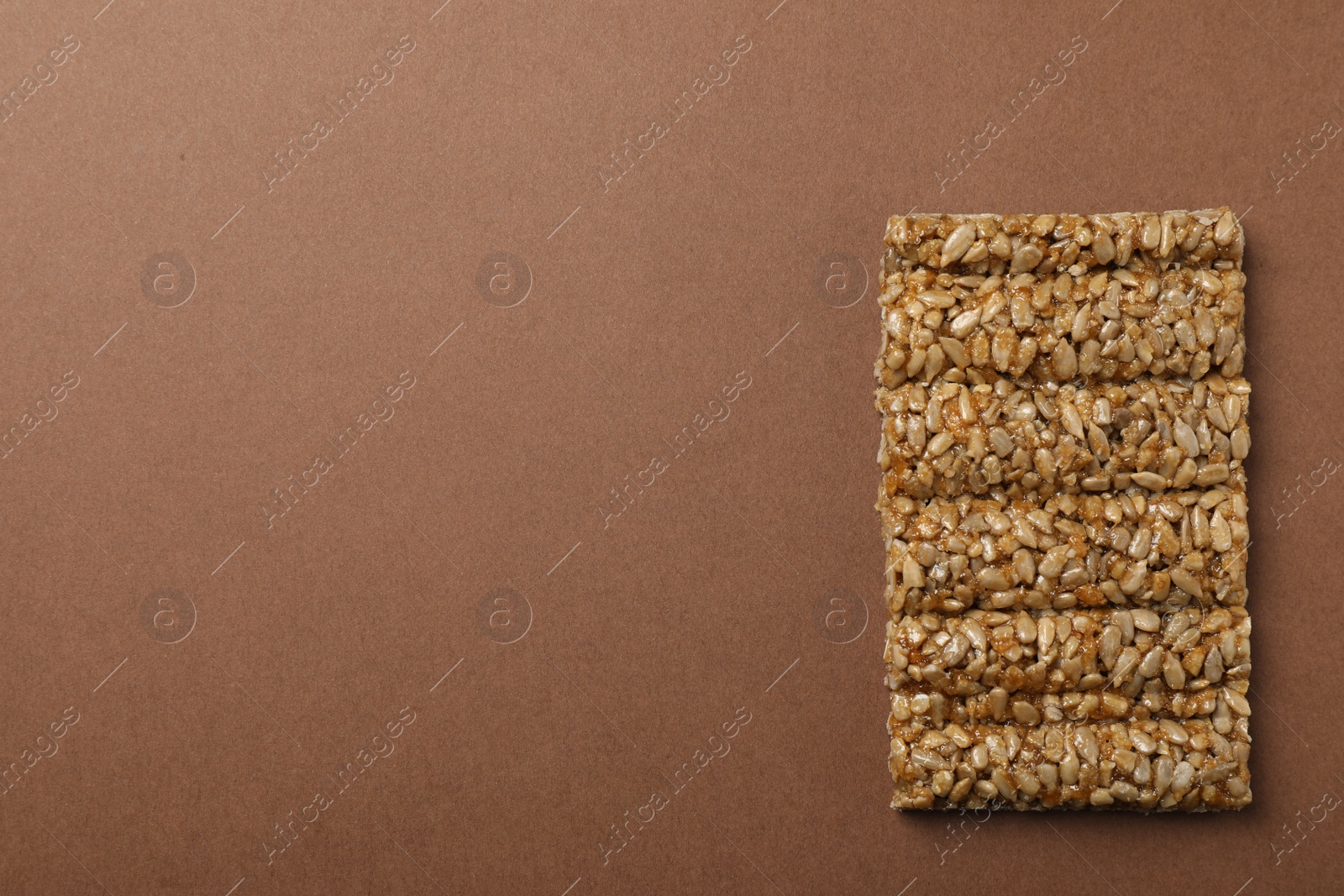 Photo of Delicious kozinaki bar on brown background, top view. Space for text