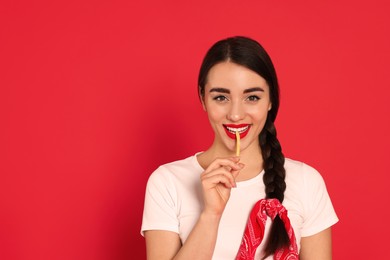 Photo of Beautiful young woman eating French fries on red background. Space for text