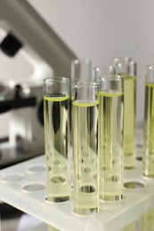 Photo of Test tubes with urine samples for analysis in holder near microscope, closeup