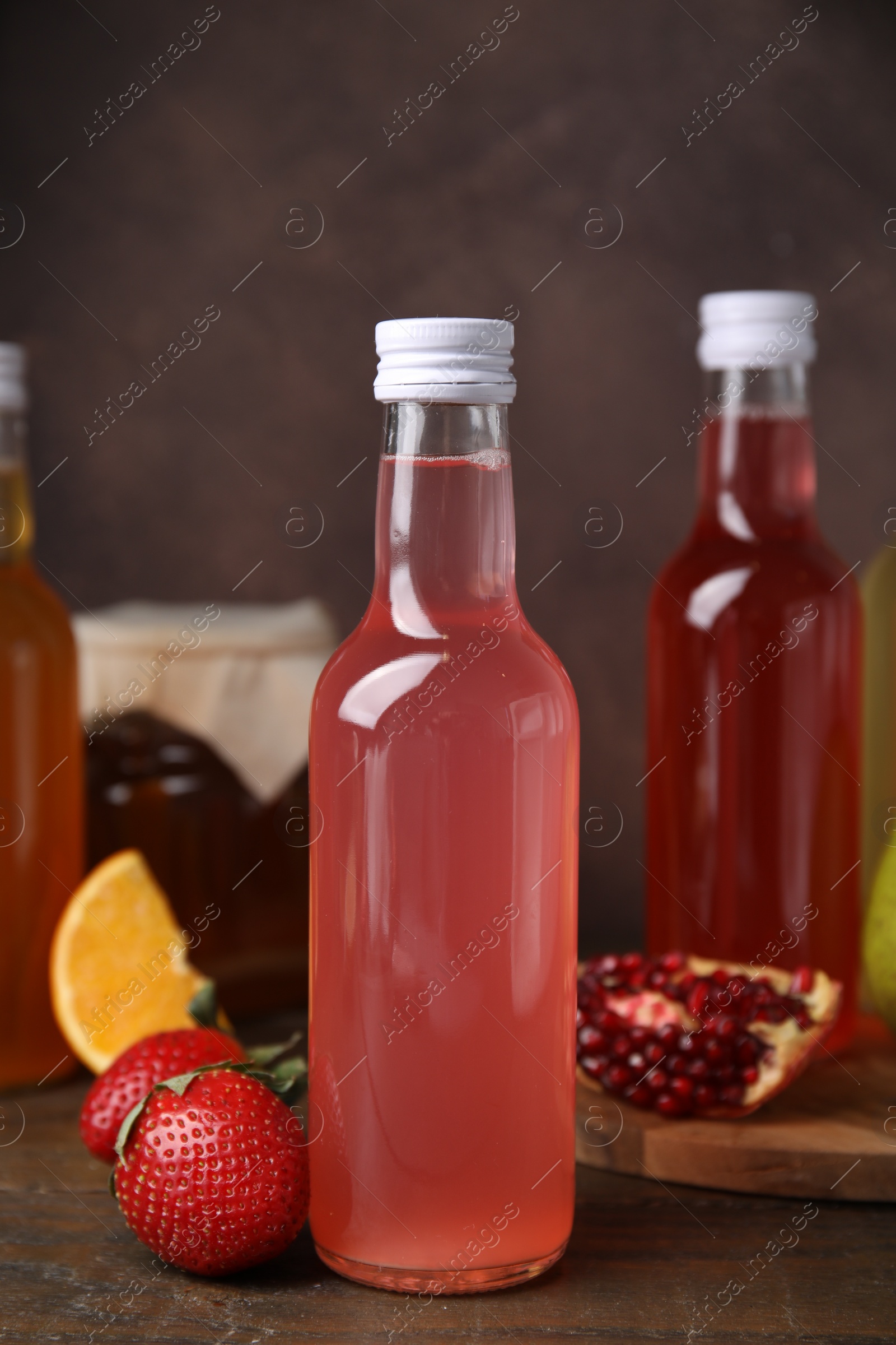 Photo of Delicious kombucha in glass bottles and fresh fruits on wooden table