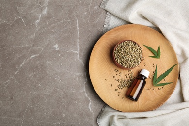 Flat lay composition with hemp seeds, bottle of extract and space for text on grey background