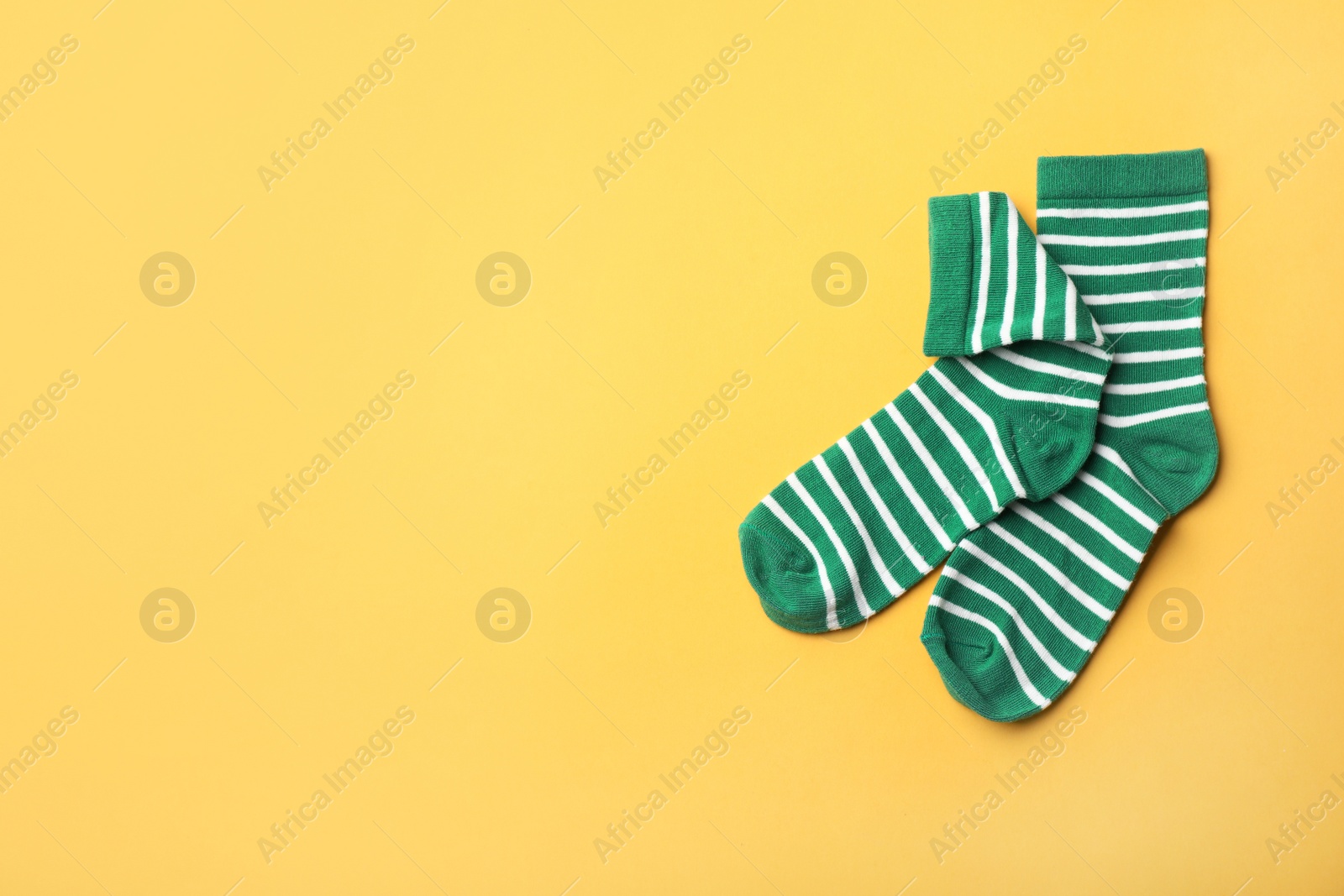 Photo of Pair of cute child socks and space for text on color background, top view