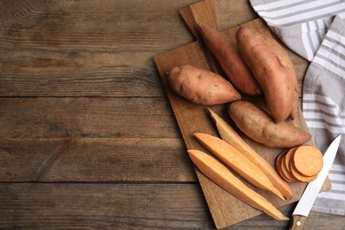 Photo of Sweet potatoes and knife on wooden table, flat lay. Space for text