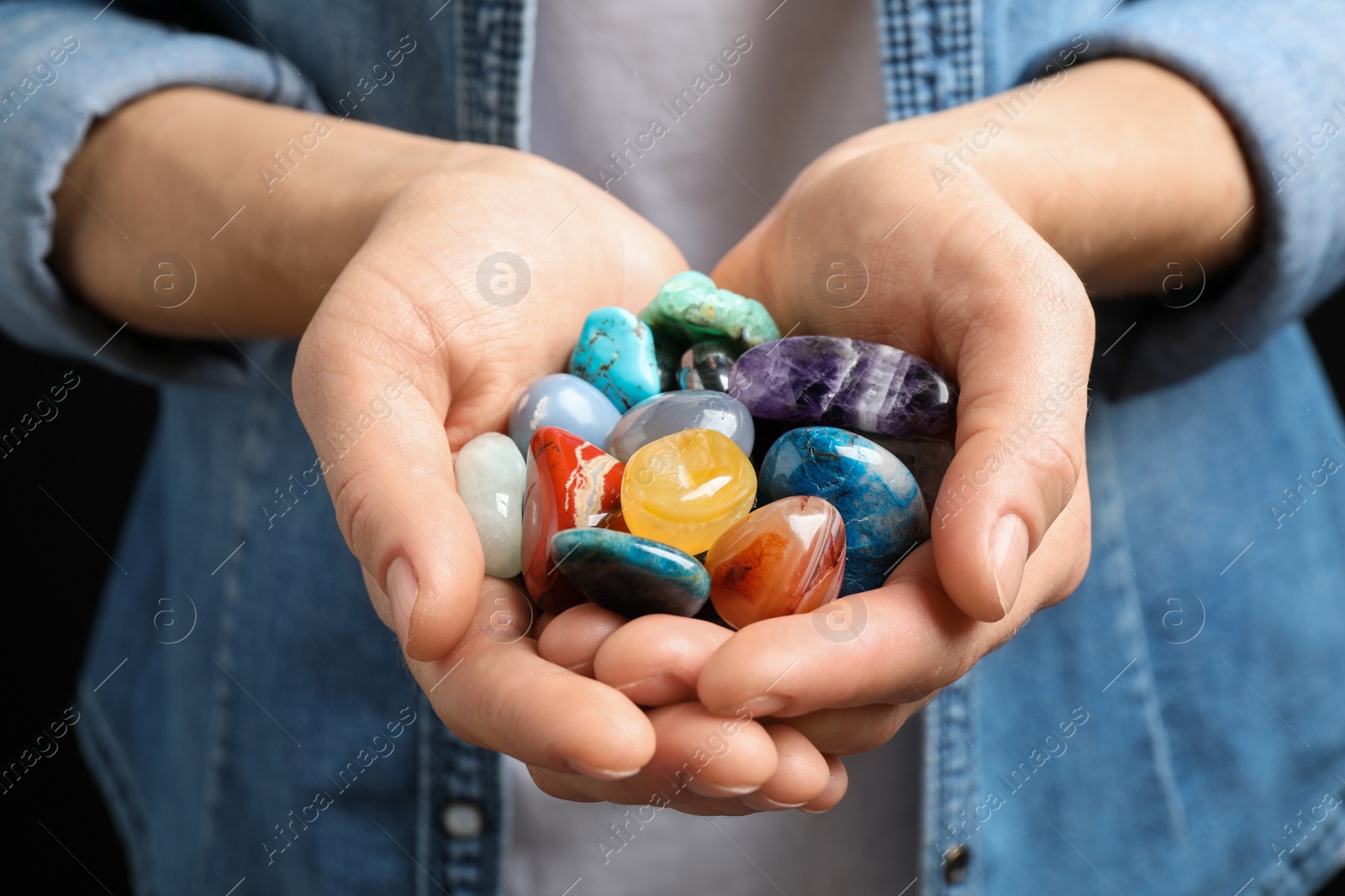 Photo of Young woman holding many beautiful gemstones, closeup