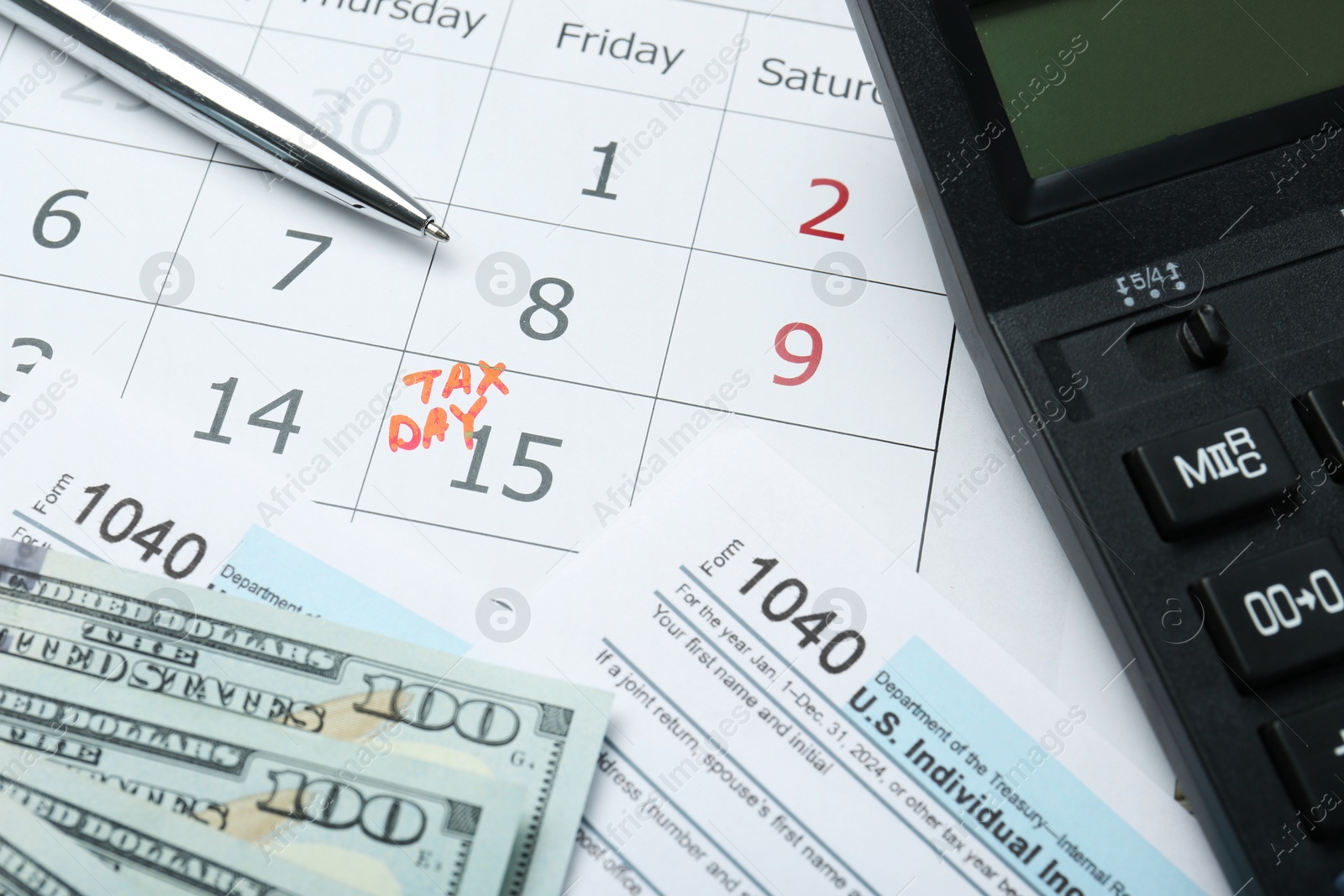 Photo of Tax day. Calendar with date reminder, documents, dollar banknotes, pen and calculator on table