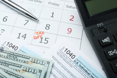 Photo of Tax day. Calendar with date reminder, documents, dollar banknotes, pen and calculator on table