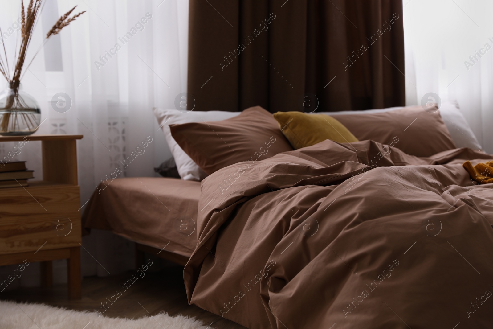 Photo of Bed with brown linens in stylish room interior