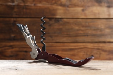 Photo of One corkscrew (sommelier knife) on wooden table, closeup