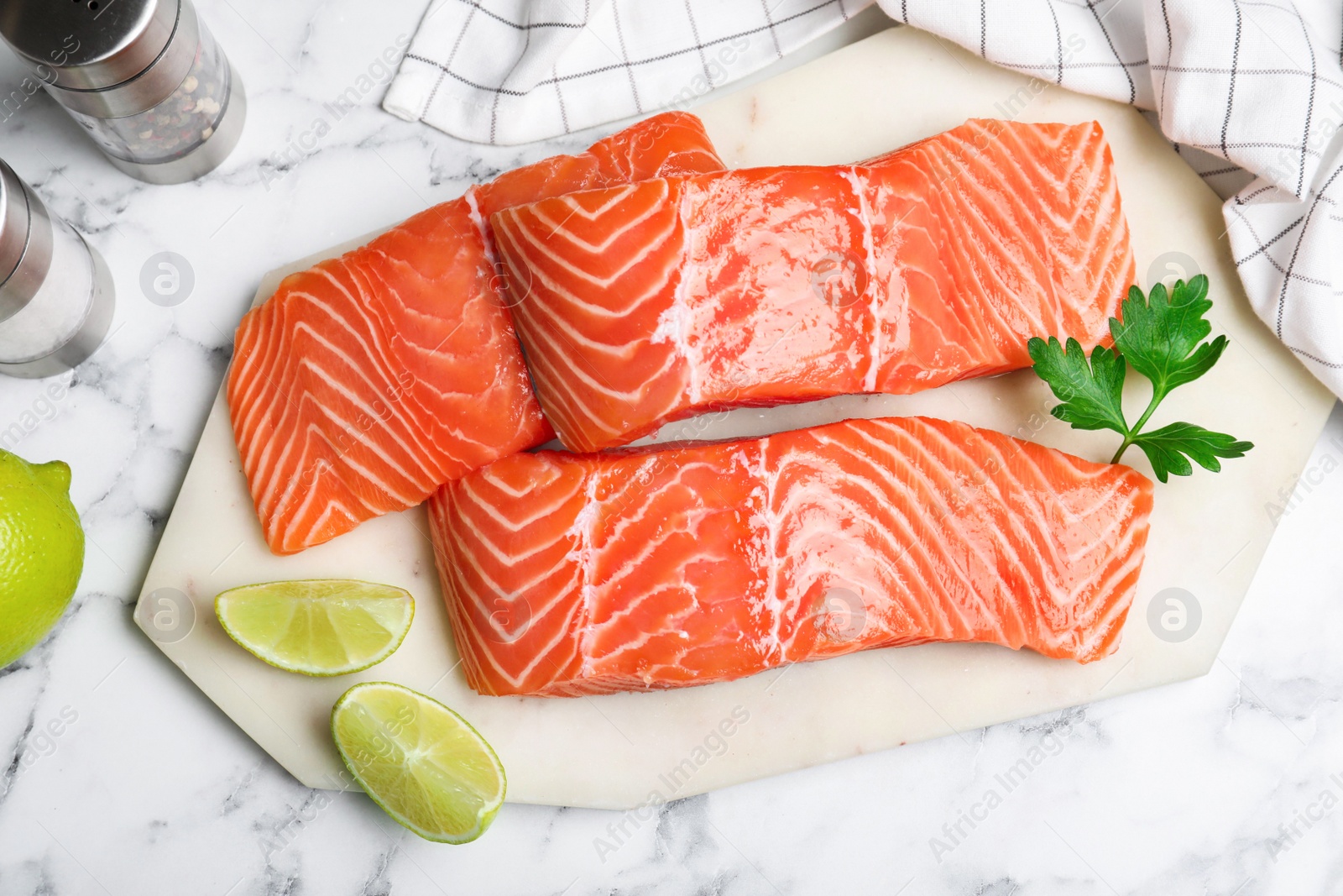 Photo of Fresh raw salmon with lime and parsley on white marble table, flat lay. Fish delicacy