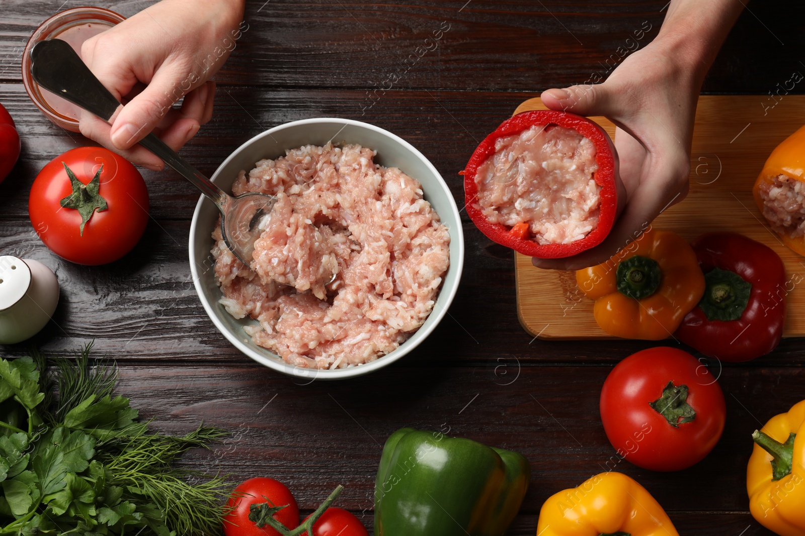 Photo of Woman making stuffed peppers with ground meat at wooden table, top view