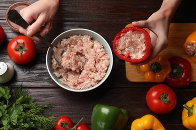 Photo of Woman making stuffed peppers with ground meat at wooden table, top view