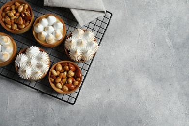 Many different tartlets on light grey table, flat lay and space for text. Tasty dessert