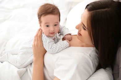 Happy woman with her cute baby on bed