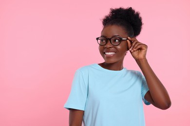 Photo of Portrait of happy young woman in eyeglasses on pink background. Space for text