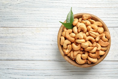 Bowl with cashew nuts on wooden table, top view. Space for text