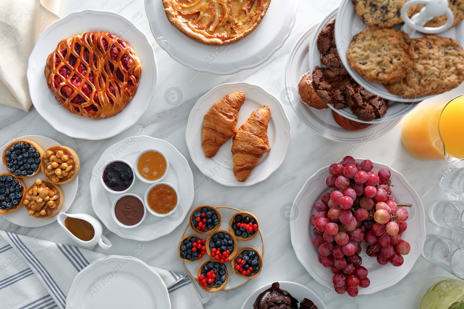 Photo of Variety of snacks on white marble table in buffet style, flat lay