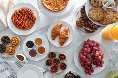 Photo of Variety of snacks on white marble table in buffet style, flat lay