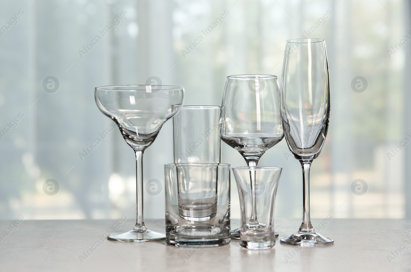 Photo of Different elegant empty glasses on grey table indoors