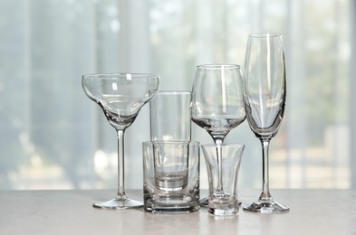 Photo of Different elegant empty glasses on grey table indoors