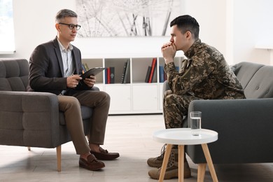 Photo of Professional psychotherapist working with military man in office