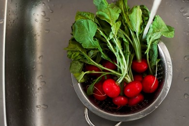 Photo of Pouring tap water into colander with radish in sink, top view