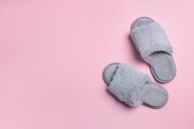Photo of Pair of soft slippers on pink background, top view. Space for text