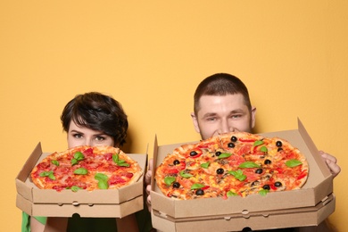 Photo of Attractive young couple with delicious pizza on color background