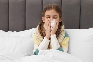 Photo of Sick girl with tissue coughing on bed at home