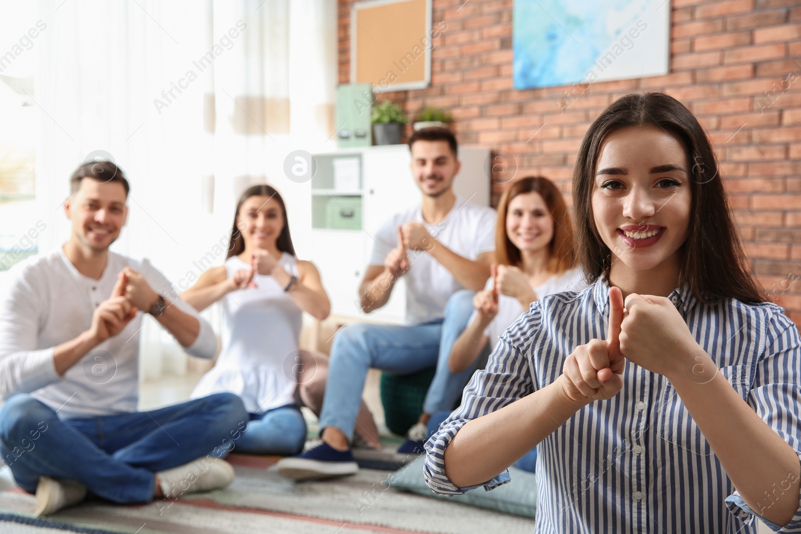 Photo of Young teacher showing sign language gesture against blurred background