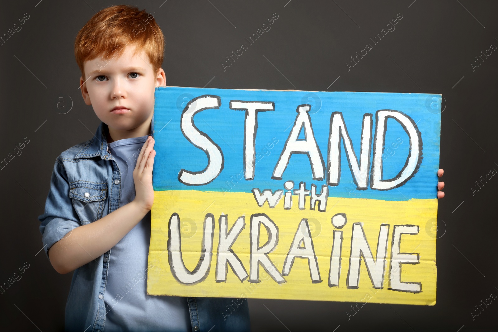Photo of Boy holding poster Stand with Ukraine against grey background