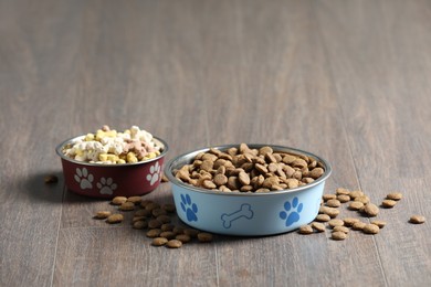 Photo of Bowls with dry dog food on wooden floor indoors