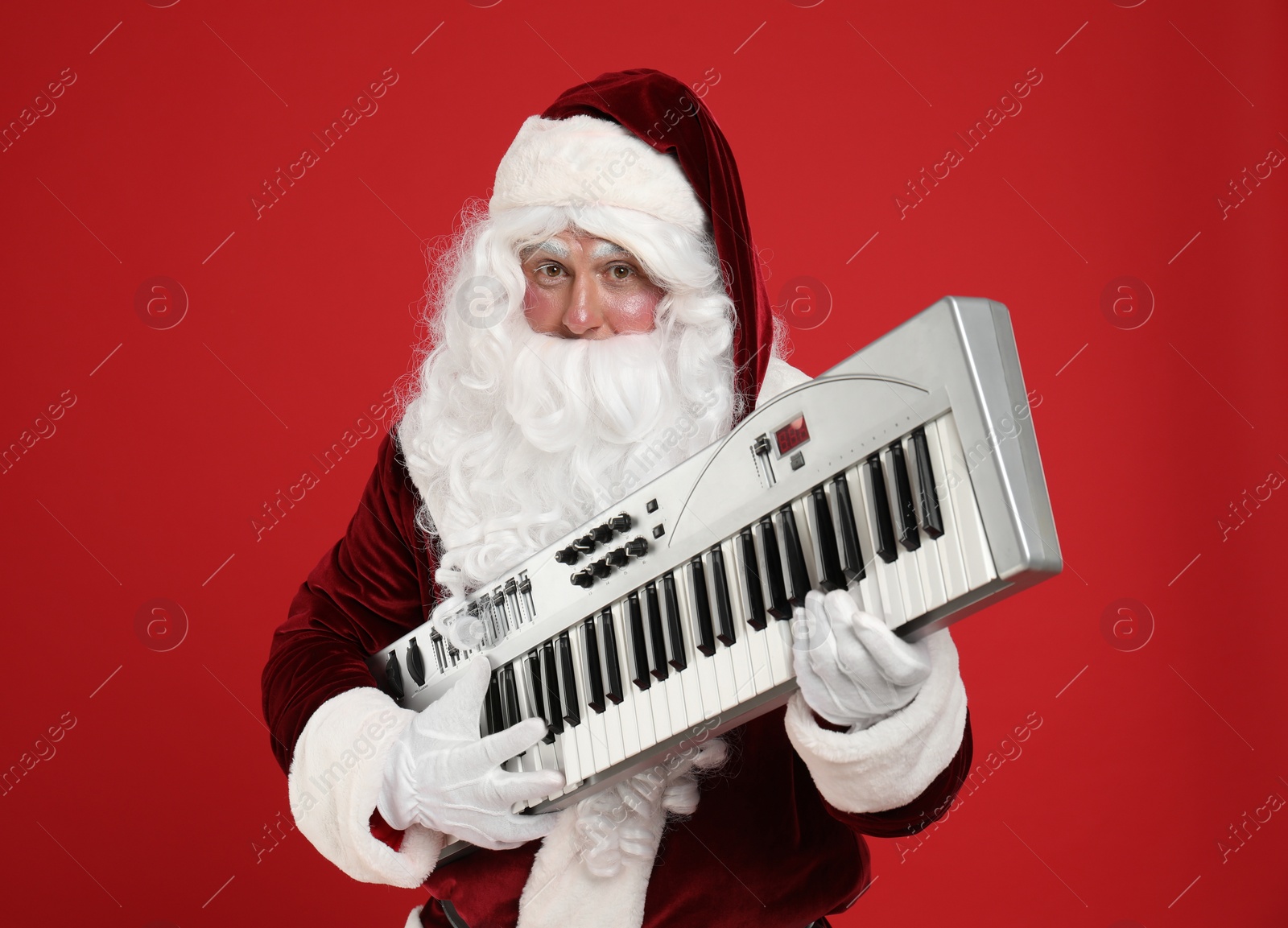 Photo of Santa Claus with synthesizer on red background. Christmas music