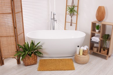 Photo of Stylish bathroom interior with soft bath mat and tub