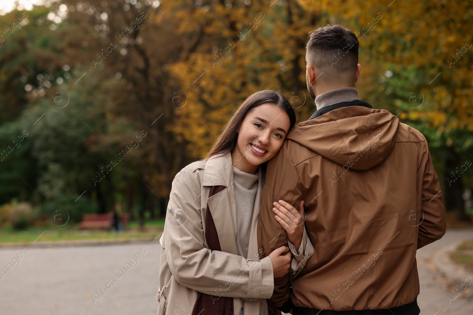 Photo of Romantic young couple spending time together in autumn park, space for text