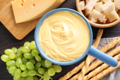 Photo of Pot with tasty cheese fondue and products on table, flat lay