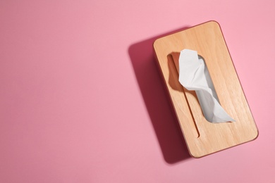 Holder with paper tissues on pink background, top view. Space for text