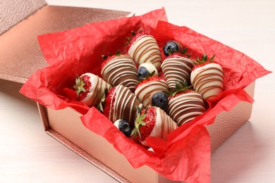 Box with delicious chocolate covered strawberries and blueberries on white table