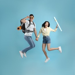 Photo of Couple of tourists jumping on light blue background