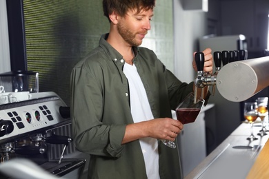 Photo of Bartender pouring fresh beer into glass in pub