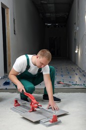 Photo of Worker using manual tile cutter in room