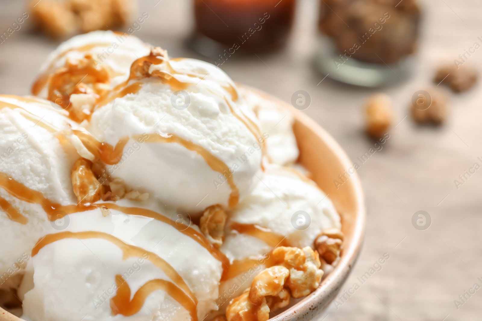 Photo of Tasty ice cream with caramel sauce and popcorn in bowl on table, closeup