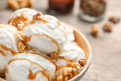 Tasty ice cream with caramel sauce and popcorn in bowl on table, closeup