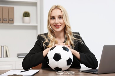 Happy woman with soccer ball at table in office