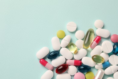 Photo of Pile of different pills on mint background, flat lay. Space for text