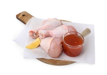 Fresh marinade, raw chicken drumsticks and lemon wedge isolated on white