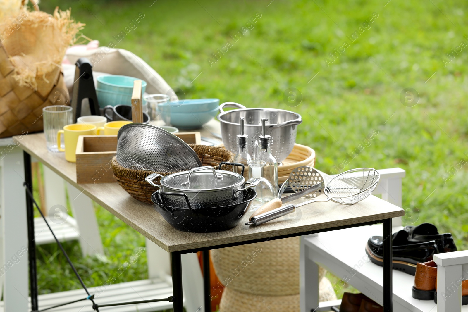 Photo of Many different items on wooden tables outdoors. Garage sale