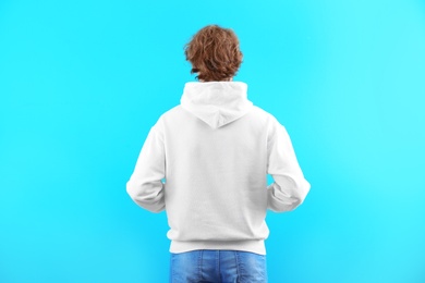 Man in hoodie sweater on color background. Space for design