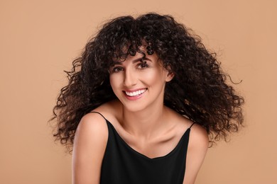 Photo of Beautiful young woman with long curly hair on beige background