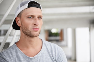 Handsome young man in stylish cap indoors, space for text