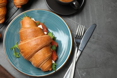 Photo of Tasty croissant sandwich with red fish on grey table, flat lay